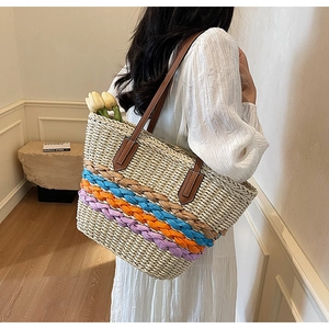 Detailed close-up of woven straw tote bag with vibrant blue, orange and purple braided straps