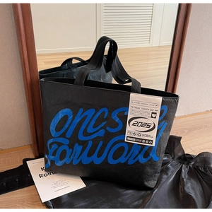 Détail du sac cabas noir avec inscription bleue et étiquette de mode latérale blanche