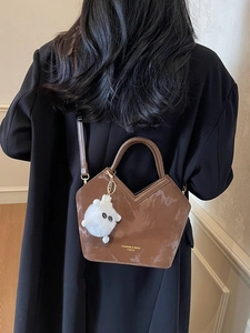Sac seau marron foncé à texture marbrée avec charme en peluche porté par un mannequin