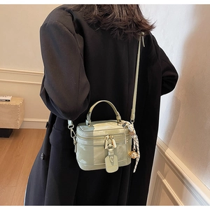 Détail du sac boîte en cuir vert menthe avec doubles fermetures dorées et foulard en soie