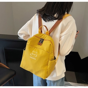 Detail of yellow waterproof nylon backpack featuring a cute cat print and fashion text
