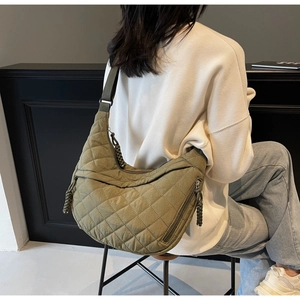 Detail of army green quilted crossbody bag with rhombic stitching and braided zipper