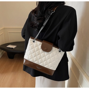 Detail of quilted leather bucket bag with silver chain strap shown on model shoulder