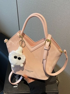 Sac à main trapèze rose avec bord en V, poignée ronde et breloque en peluche blanche