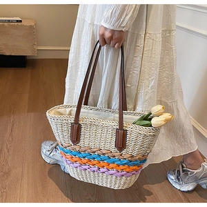 Detail of hand-woven straw tote with colorful rope stripes and brown leather handles