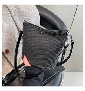 Détail du sac bandoulière noir à texture tressée avec des boucles en métal argenté