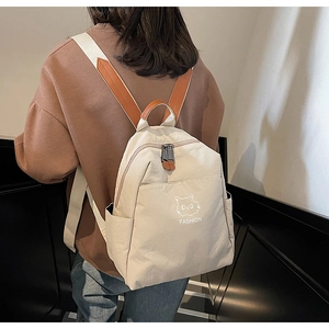 Detail of the minimalist nylon backpack showing the contrast straps and cat graphic