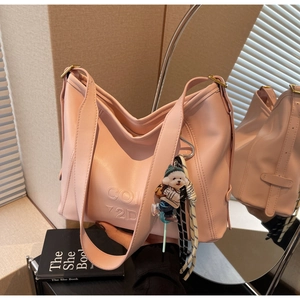 Macro detail of pink leather underarm bag with relief logo and cute dog charm