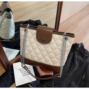 Close-up of quilted contrast bucket bag featuring cream and dark brown faux leather