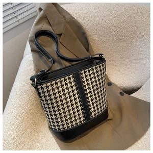 Détail du sac seau pied-de-poule avec coutures blanches sur bandoulière noire