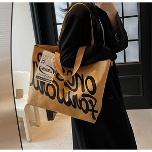 Détail d'un grand sac cabas moutarde avec lettrage artistique et étiquette mode casual