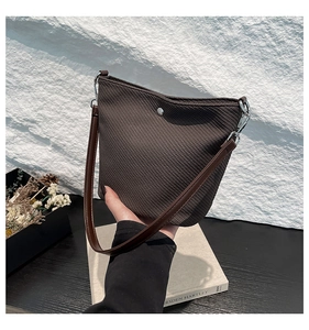 Gros plan du sac seau marron foncé montrant le tissu texturé et les boucles argentées