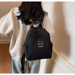 Detail of black waterproof nylon backpack with white minimalist cat embroidery and logo
