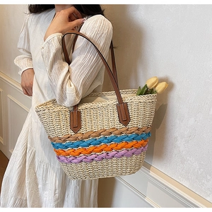 Detail of hand-woven straw tote with colorful stripes and brown leather shoulder straps