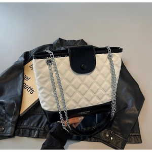 Detailed shot of quilted contrast bucket bag with silver chain strap on leather jacket