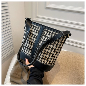 Détails du sac seau en tissu pied-de-poule avec finitions en cuir noir et boucles dorées