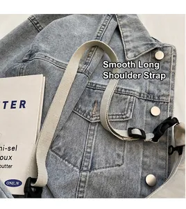 Dettaglio della borsa in denim azzurro con tracolla in tela grigia regolabile e bottoni in metallo