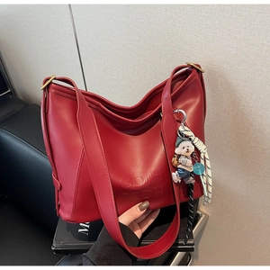 Detail of red faux leather hobo bag featuring embossed lettering and a cute bear charm