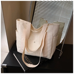Detail of off-white canvas tote bag with side pockets and magnetic closure