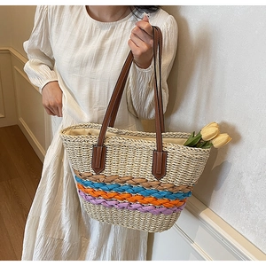 Detail of handwoven straw tote bag featuring colorful stripes and brown leather straps