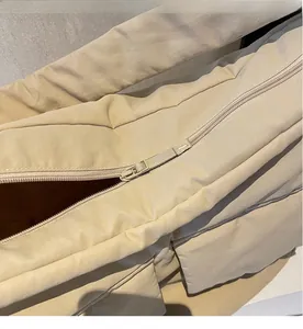 Close-up of smooth zipper closure and quilted nylon fabric on beige shoulder bag