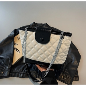 Macro shot of quilted stitching detail and silver chain strap on bicolor bucket bag
