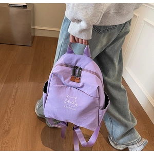 Detail of purple waterproof nylon backpack featuring cat graphic and leather zipper pulls