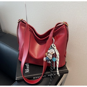 Close-up of deep red tote bag with COFH 2DN lettering and cute dog charm accessories