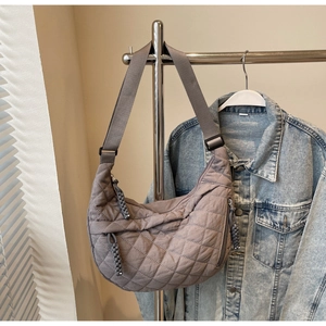 Close-up of grey quilted crescent bag with diamond stitching and knotted zipper pulls