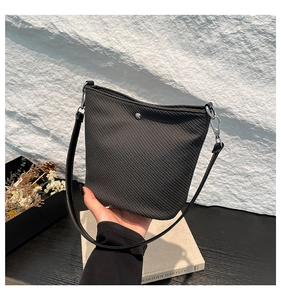 Détail du sac seau noir tressé avec boucle métallique et bandoulière en cuir