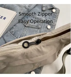 Dettaglio della cerniera nera scorrevole e del tirante tondo su borsa in nylon grigio
