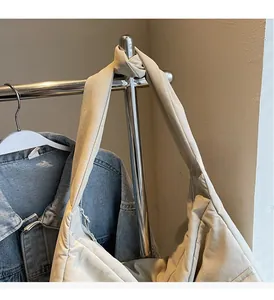 Detail of a beige tote bag with a unique knotted handle design and soft creased texture