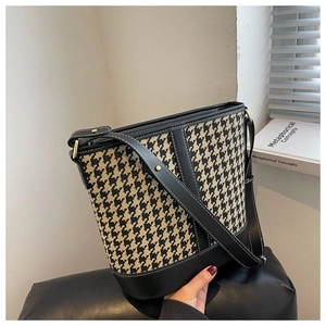 Detail of houndstooth bucket bag with black leather trim and gold-tone hardware