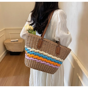 Detail of straw tote bag with colorful braided stripes and brown leather shoulder straps