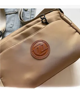 Vue détaillée du sac bandoulière en nylon kaki avec logo en cuir et poches zippées
