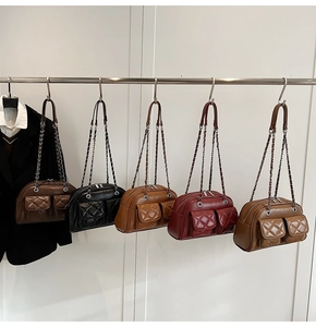Collection of vintage quilted crossbody bags in brown, black, and red hanging on metal hooks