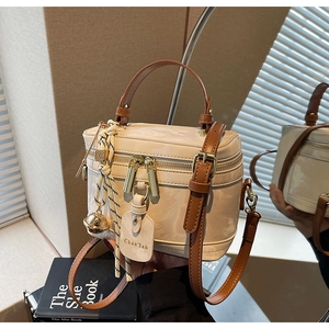 Détail d'un sac boîte blanc crème avec fermetures dorées et poignée marron élégante