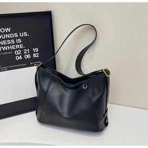 Close-up of matte black leather underarm bag with gold hardware and embossed lettering
