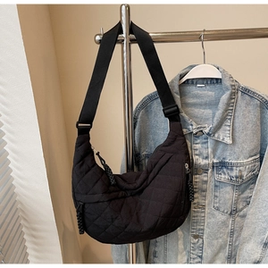 Close-up of black quilted nylon crescent bag featuring adjustable strap and woven zipper pull
