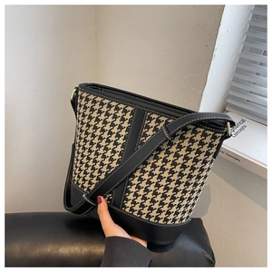 Detail of houndstooth bucket bag with leather trim and adjustable shoulder strap