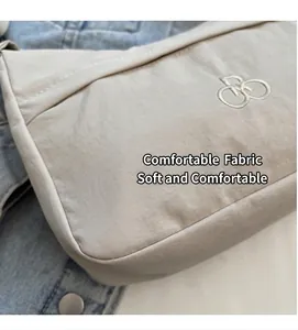 Dettaglio ravvicinato della borsa in nylon beige con tessuto morbido e logo ricamato