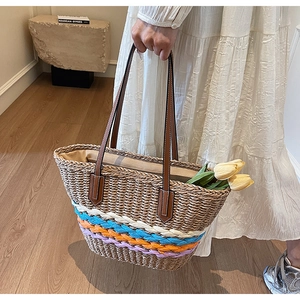 Detail of hand-woven straw bucket bag with colorful stripes and brown leather handles