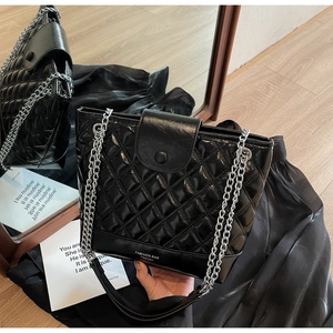 Detail of black quilted leather bucket bag with silver chain strap and fashion logo