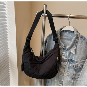 Detail of black quilted moon bag featuring diamond stitching and adjustable wide strap