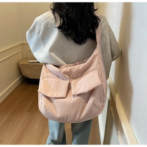 Detail shot of light pink quilted tote bag with dual front pockets on a model