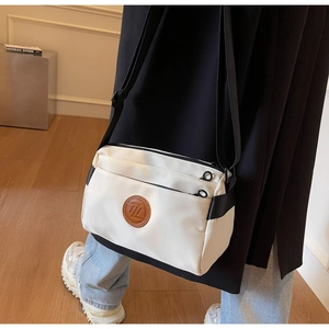 Détail d'un sac bandoulière blanc minimaliste avec double fermeture éclair
