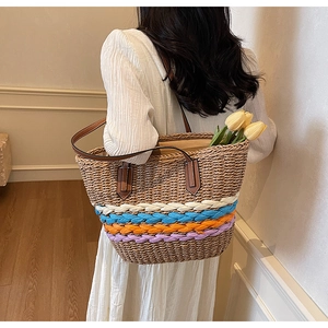 Detail of hand-woven straw tote with colorful stripes and slim brown leather handles