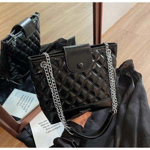 Detailed view of the quilted texture and silver chain strap on the black bucket bag