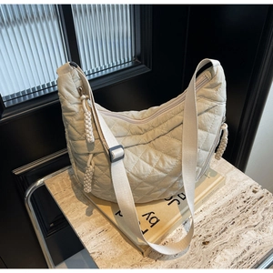 Detail of beige quilted hobo bag with adjustable wide strap and woven knot details