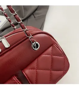 Close-up of red quilted leather bag with silver metal chain and refined stitching detail